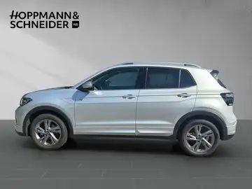 Das Bild zeigt einen VW T-Cross von der Seite in silberner Farbe. Im Hintergrund ist das Händlerlogo 'HOPPMANN & SCHNEIDER' sichtbar.