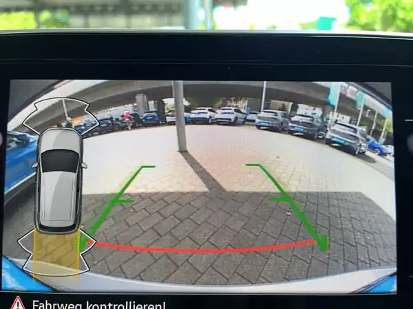 Das Bild zeigt die Rückfahrkameraansicht eines Fahrzeugs im Innenraum, mit einem klaren Blick auf das Parkplatzumfeld.
