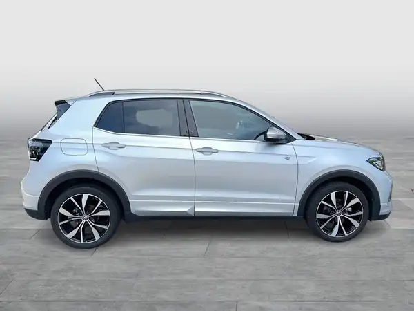 Das Bild zeigt einen silbernen VW T-CROSS, aufgenommen von der Seite.