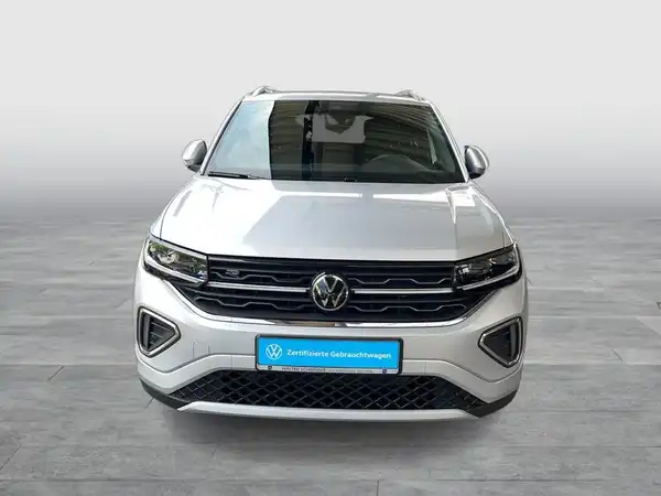 Ein Bild von einem weißen VW T-CROSS, aufgenommen von vorne. Das Foto enthält das Händlerinformationslogo und markante Texteinblendungen.