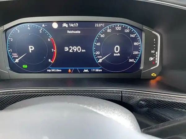 Das Bild zeigt das Innenleben eines VW T-Cross mit einem Blick auf das Armaturenbrett und das digitale Display. Die Farbe des Innenraums ist schwarz. Es sind markante Texteinblendungen auf dem Display sichtbar.