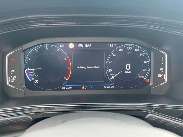 Die Innenaufnahme zeigt das Armaturenbrett des Fahrzeugs mit einem digitalen Tacho und einer Warnmeldung. Die Interieurfarbe ist schwarz.