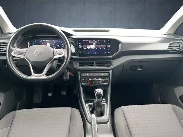 Das Bild zeigt das Innere eines VW T-Cross, aufgenommen aus der Perspektive des Fahrers mit schwarzem Interieur.