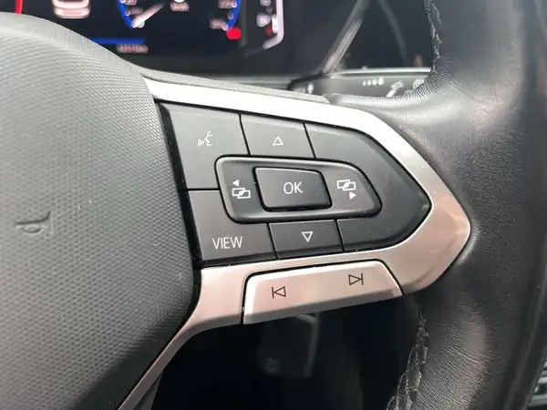 Das Bild zeigt das Innenraum eines VW T-CROSS mit einem schwarzen Interieur und einem Display, das verschiedene Medienoptionen anzeigt.