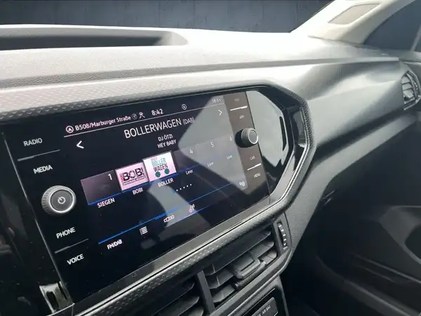 Das Bild zeigt das Innenraum eines VW T-CROSS, mit einem schwarzen Interieur. Auf dem Display sind verschiedene Funktionen und Einstellungen sichtbar.