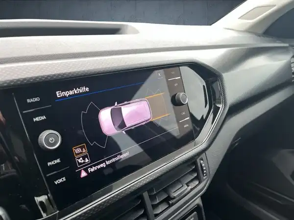 Das Bild zeigt das Innenraum des VW T-CROSS mit schwarzem Interieur und einem Bildschirm, der Parkplatzhilfen anzeigt.