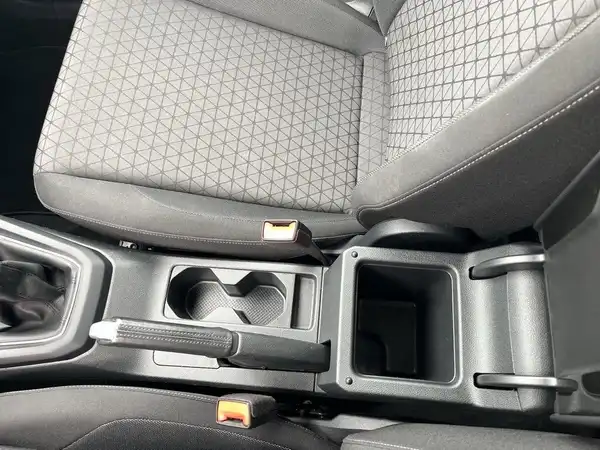 Das Bild zeigt den Innenraum eines Fahrzeugs, insbesondere einen Sitz und die Mittelkonsole mit einem schwarzen, gemusterten Stoff.