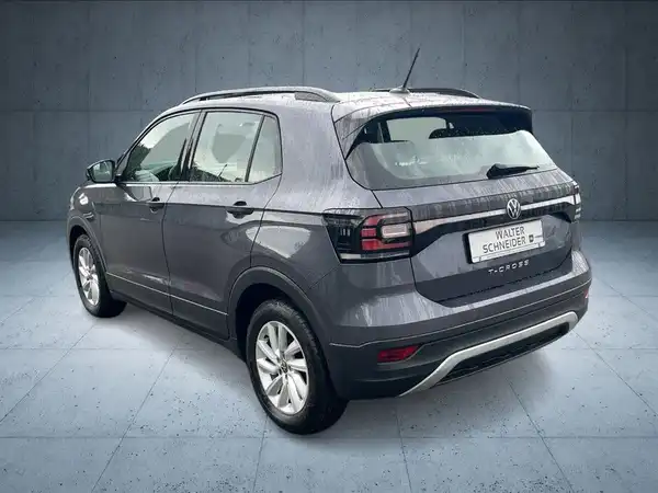Das Bild zeigt einen VW T-CROSS aus der Rückansicht. Das Fahrzeug ist grau und trägt das Händlerlogo 'WALTER SCHNEIDER'.