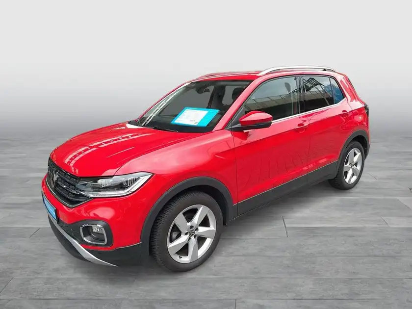 Das Bild zeigt einen roten VW T-Cross von der Seite. Es enthält markante Texteinblendungen.