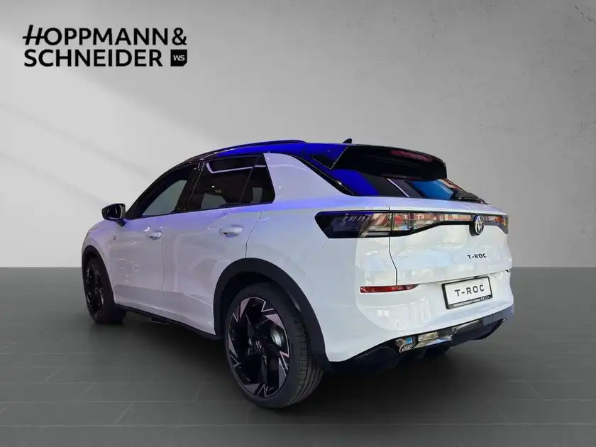 Das Bild zeigt einen VW T-ROC von hinten in weißer Farbe und enthält das Händlerlogo HOPPMANN & SCHNEIDER.