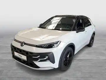 Das Bild zeigt einen weißen VW T-Roc, aufgenommen von der Seite. Es gibt ein Händlerlogo und eine Texteinblendung mit dem Hinweis 'Sofort verfügbar'.