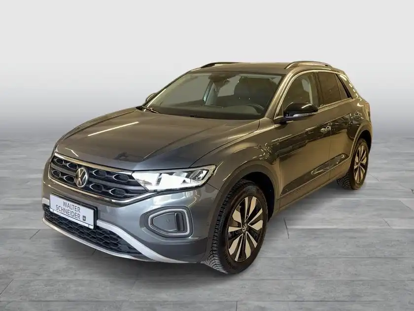 Das Bild zeigt einen grauen VW T-Roc von vorne, mit sichtbarem Händlerlogo und markanten Texteinblendungen.
