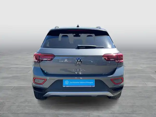 Das Bild zeigt den Volkswagen T-Roc von hinten in grauer Farbe. Es enthält ein Händlerlogo und handelt sich um ein Fahrzeugbild.