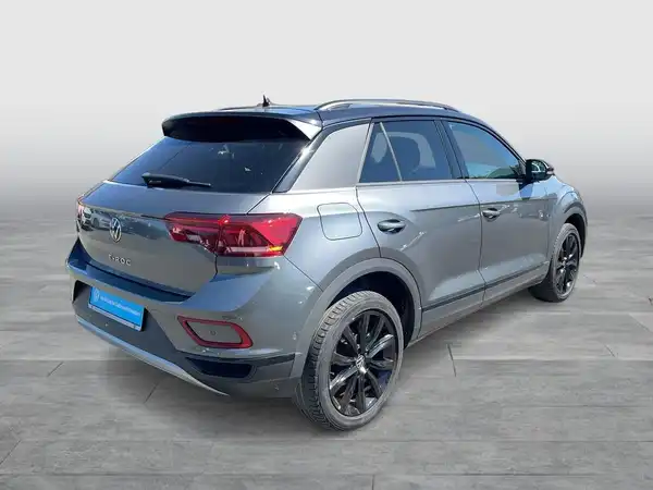 Das Bild zeigt einen grauen VW T-ROC aus der Rückansicht.