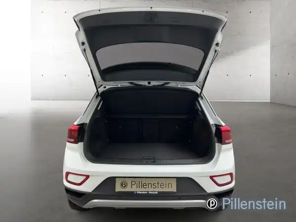 Das Bild zeigt den Kofferraum eines weißen VW T-ROC aus der hinteren Ansicht, mit dem Händlerlogo von Pillenstein.