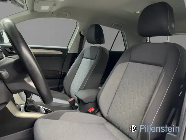 Das Bild zeigt den Innenraum eines VW T-ROC aus der Sicht des Fahrers, mit schwarzen und grauen Sitzen.