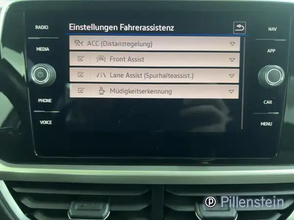 Das Bild zeigt das Innenleben eines VW T-ROC, insbesondere das Navigations- und Infotainmentsystem mit Einstellungen für Fahrerassistenzsysteme. Das Interieur ist schwarz.