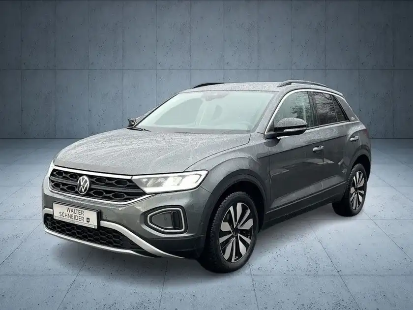 Das Bild zeigt einen grauen VW T-ROC von vorne mit dem Händlerlogo im unteren Bereich.