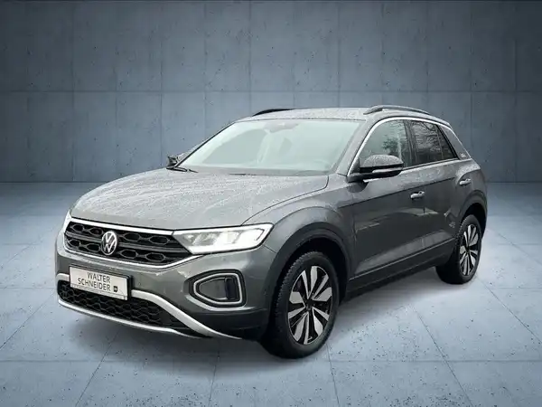 Das Bild zeigt einen grauen VW T-ROC von vorne mit dem Händlerlogo im unteren Bereich.