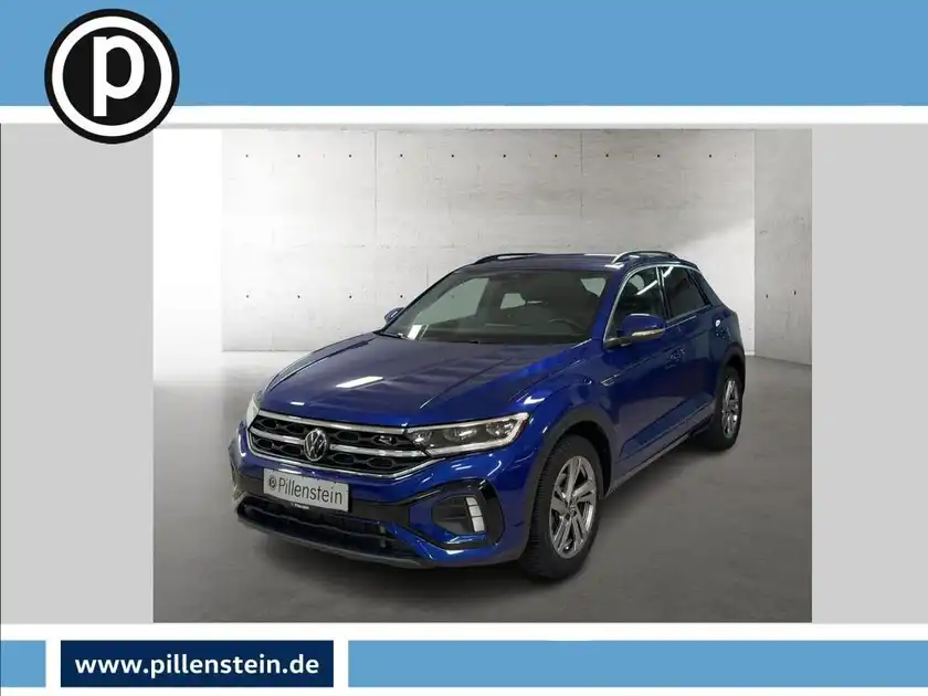 Das Bild zeigt einen blauen VW T-ROC aus der Frontalansicht. Das Händlertlogo ist eingeblendet.