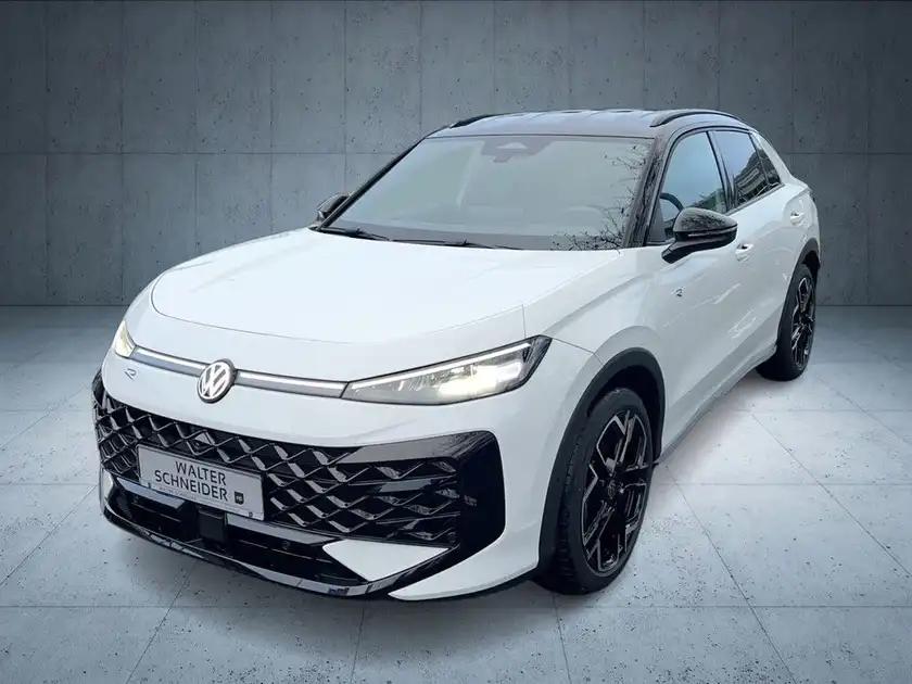 Das Bild zeigt einen weißen Volkswagen T-Roc aus der Vorderansicht mit Händlerlogo und Texteinblendungen.