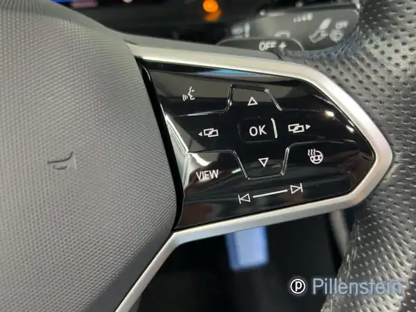 Detailaufnahme des Innenraums eines VW T-ROC CABRIOLET, zeigt die Bedienelemente am Lenkrad in schwarzer Farbe.
