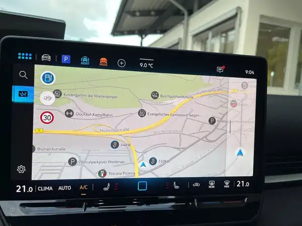 Das Bild zeigt das Innenleben eines Fahrzeugs mit einem Navigationssystem auf dem Bildschirm, auf dem eine Karte zu sehen ist.