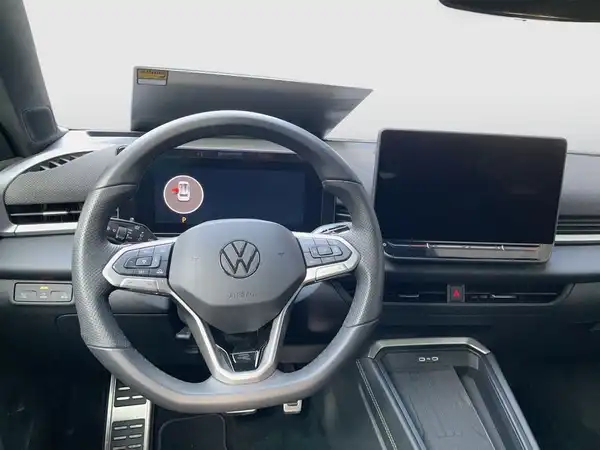 Das Bild zeigt das Innere eines VW T-ROC mit einem schwarzen Interieur. Es wurde von der Fahrerseite aufgenommen.