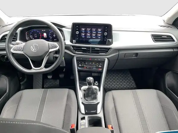 Das Bild zeigt das Innere eines VW T-ROC mit einem schwarzen Interieur und grauen Akzenten. Es handelt sich um eine Innenaufnahme des Fahrzeugs.