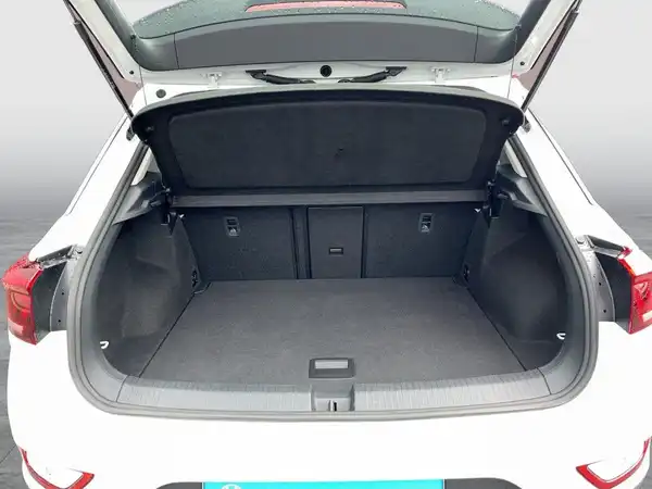 Auf dem Bild ist der Kofferraum eines weißen VW T-ROC zu sehen, aufgenommen von hinten.