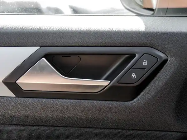 Das Bild zeigt den Innenraum eines VW T-ROC, insbesondere die Rückbank. Die Farbe des Fahrzeugs ist weiß und das Interieur ist grau.