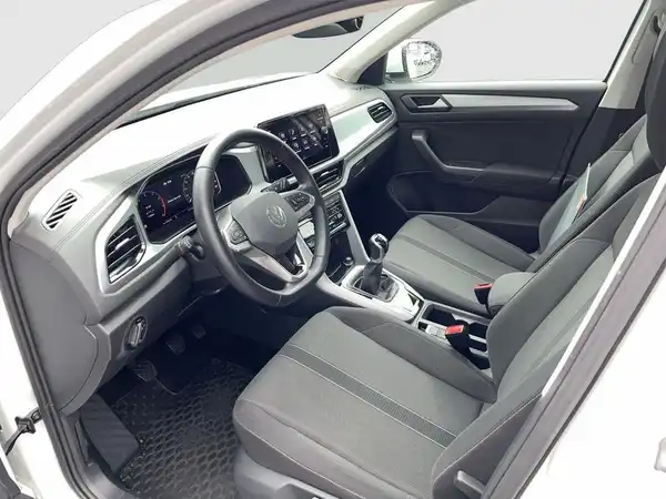 Das Bild zeigt die Innenansicht eines VW T-ROC mit schwarzen Sitzen und Armaturen.