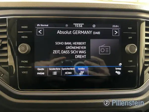 Das Bild zeigt das Innenraumdisplay eines VW T-ROC. Es zeigt eine Radiostation mit dem Namen 'Absolut GERMANY'. Das Interieur ist schwarz und es ist ein Händlerlogo eingeblendet.