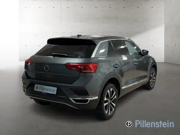 Das Bild zeigt einen grauen VW T-ROC von hinten. Es enthält ein Händlerlogo.