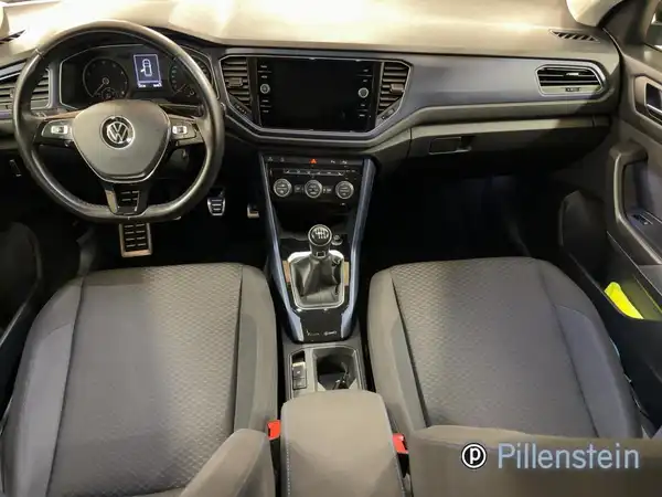 Innenaufnahme eines VW T-ROC mit schwarzem Interieur und einem Händlerlogo.