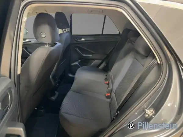Das Bild zeigt den Innenraum eines VW T-ROC von der Rückseite. Die Sitze sind schwarz und das Händlerlogo ist sichtbar.