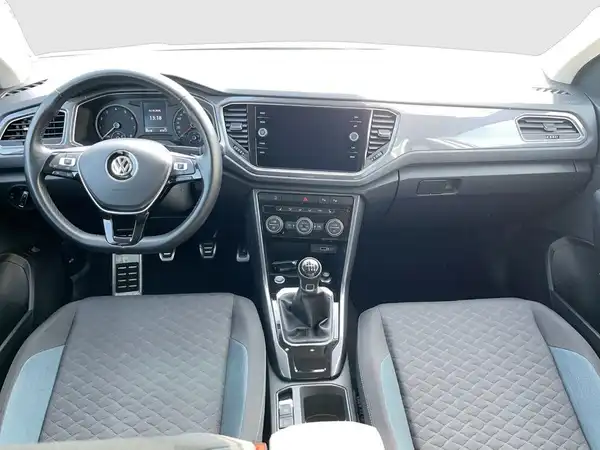 Das Bild zeigt das Innere eines VW T-ROC mit grauen Sitzen und blauen Akzenten.