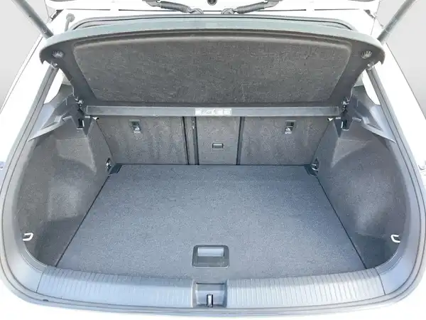 Das Bild zeigt den Kofferraum eines weißen VW T-ROC aus der Rückansicht. Der Innenraum ist schwarz und aus Stoff.