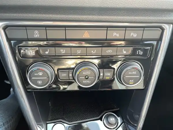 Innenaufnahme des Fahrzeugs VW T-Roc mit Klimaanpassungskontrollen und schwarzem Interieur.
