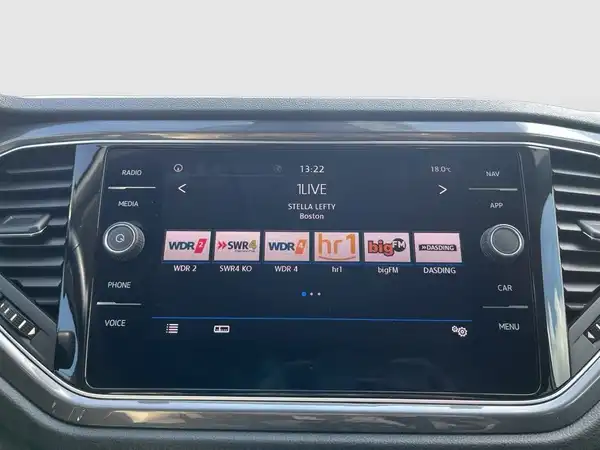 Innenaufnahme des Fahrzeugs VW T-ROC mit einem Display, das verschiedene Radiosender anzeigt.