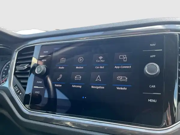 Das Bild zeigt das Innenraumdisplay eines VW T-Roc, das schwarze Interieur hat. Es enthält markante Texteinblendungen wie "Radio", "Navigation" und "Verkehr".