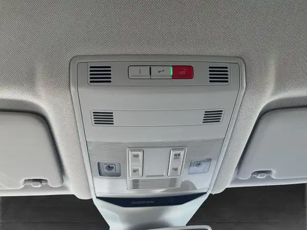 Das Bild zeigt die Innenansicht des Fahrzeugs, insbesondere die Deckenleuchte sowie einige Bedienelemente und Lüftungsöffnungen in hellgrauer Farbe.