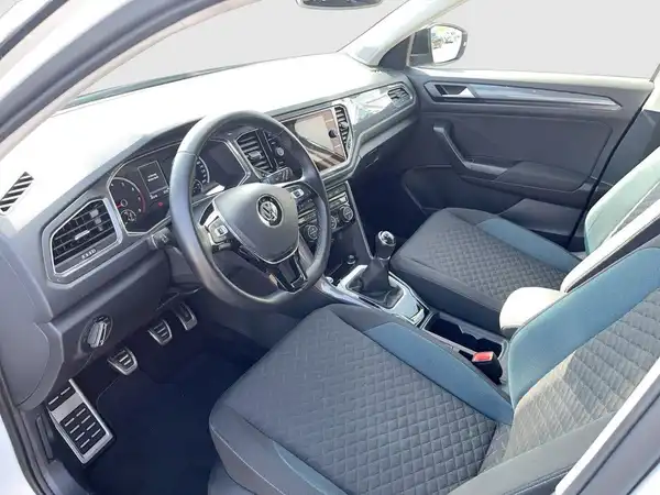 Das Bild zeigt den Innenraum eines VW T-ROC in schwarz mit blauen Akzenten.