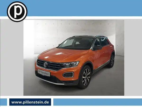 Das Bild zeigt einen VW T-ROC aus der Frontansicht, in der Farbe Orange. Es enthält ein Händlerlogo und markante Texteinblendungen.