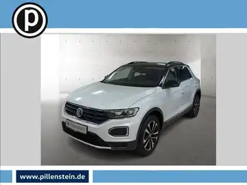 Das Bild zeigt einen weißen VW T-Roc, aufgenommen von vorne. Das Händlerinformationslogo ist sichtbar und es sind markante Texteinblendungen vorhanden.