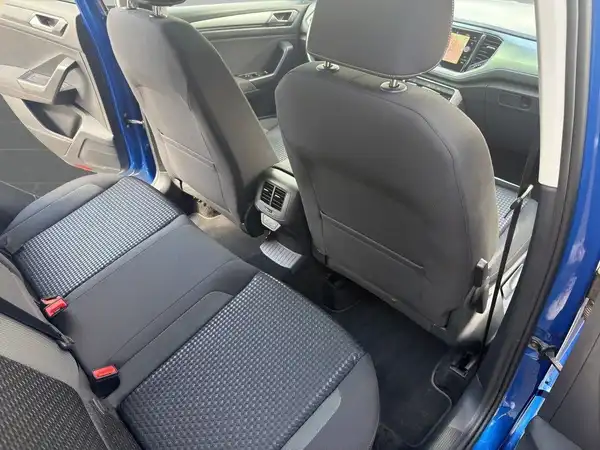 Die Innenaufnahme zeigt die Rücksitze eines blauen VW T-ROC. Die Sitze sind dunkelgrau mit strukturiertem Stoff.