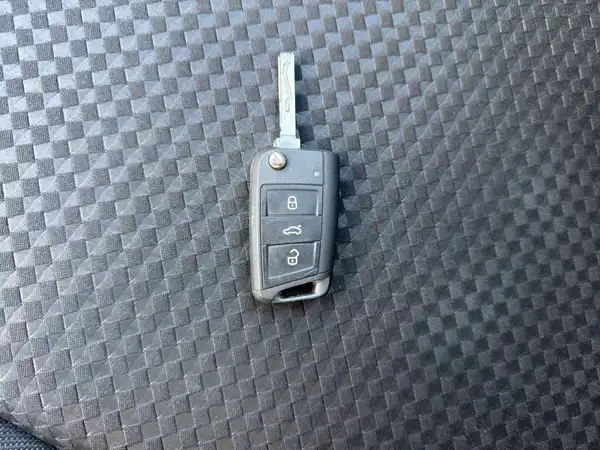 Das Bild zeigt einen Fahrzeugschlüssel auf einem schwarzen, strukturierten Untergrund.