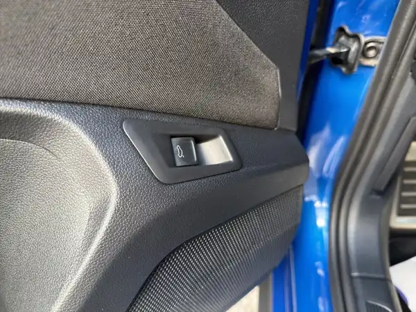 Das Bild zeigt den Innenraum eines VW T-ROC von der Seite der Fahrertür, mit einem Detailansicht des Tür- und Fensterbedienelements in schwarzer Farbe.