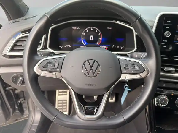 Das Bild zeigt das Innenleben eines VW T-ROC, aufgenommen aus der Sicht des Fahrers. Das Lenkrad und das Armaturenbrett sind sichtbar.