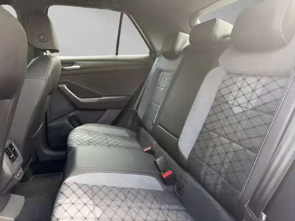 Innenaufnahme des VW T-ROC von hinten, zeigt die Rücksitze in schwarz mit grauen Akzenten und gestepptem Design.